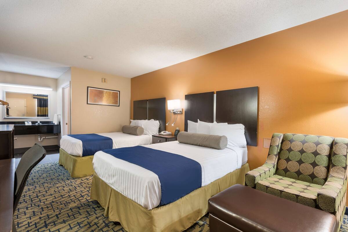 Une chambre d’hôtel avec deux lits, un bureau, une chaise et une petite table.
