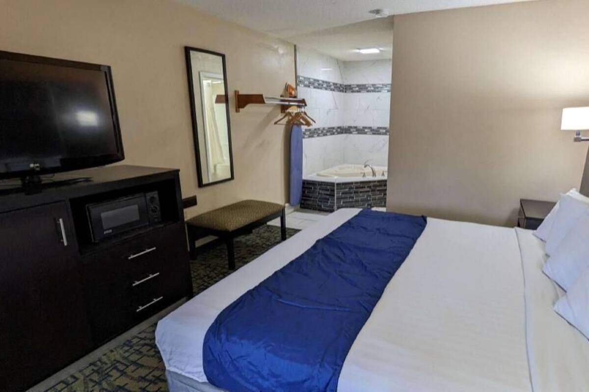 Une chambre d’hôtel équipée d’un lit, d’une télévision, d’un bureau et d’une salle de bain avec baignoire.