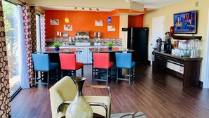 A modern kitchen with a breakfast bar, a refrigerator, and a coffee station.