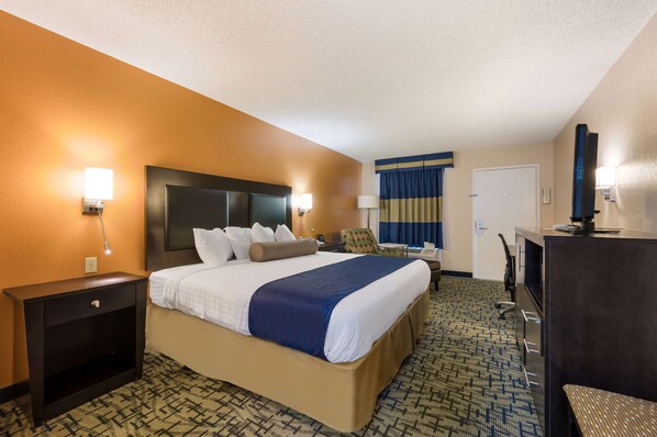 Une chambre d’hôtel avec un grand lit, un bureau, une chaise, une télévision et une porte.