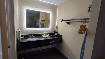 A bathroom with a double sink, a large mirror with a light, a hairdryer, and a towel rack.