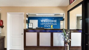 A reception desk with a 'Welcome to the Magnolia State' sign, a white door, and a potted plant. - SureStay Hotel by Best Western Meridian (Meridian)