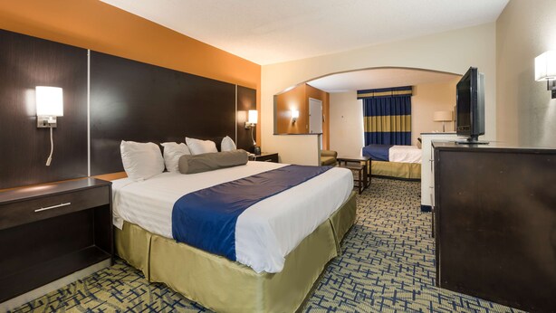 A hotel room with a large bed, a desk, a television, and a bathroom visible through an archway. - SureStay Hotel by Best Western Meridian (Meridian)