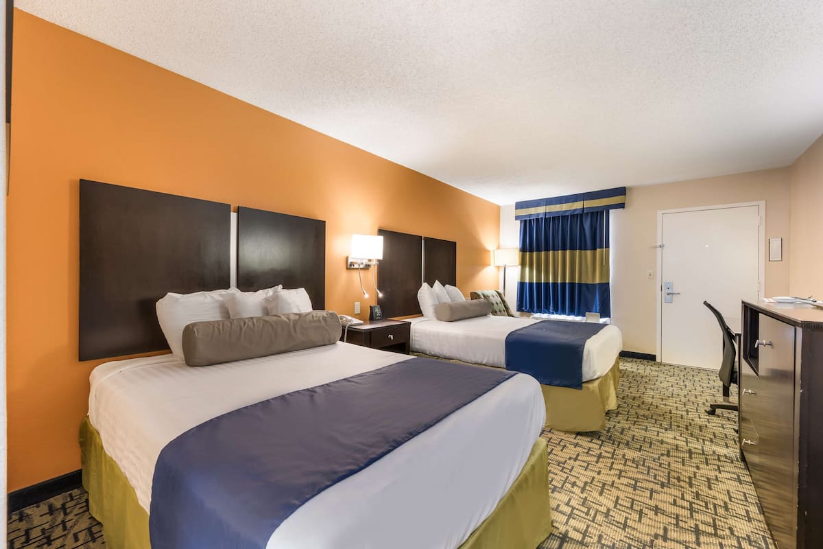 Une chambre d’hôtel avec deux lits, un bureau et une armoire.