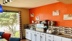 A kitchen with white cabinets, a granite countertop, and a red backsplash. There are signs on the wall indicating available food items. - SureStay Hotel by Best Western Meridian (Meridian)