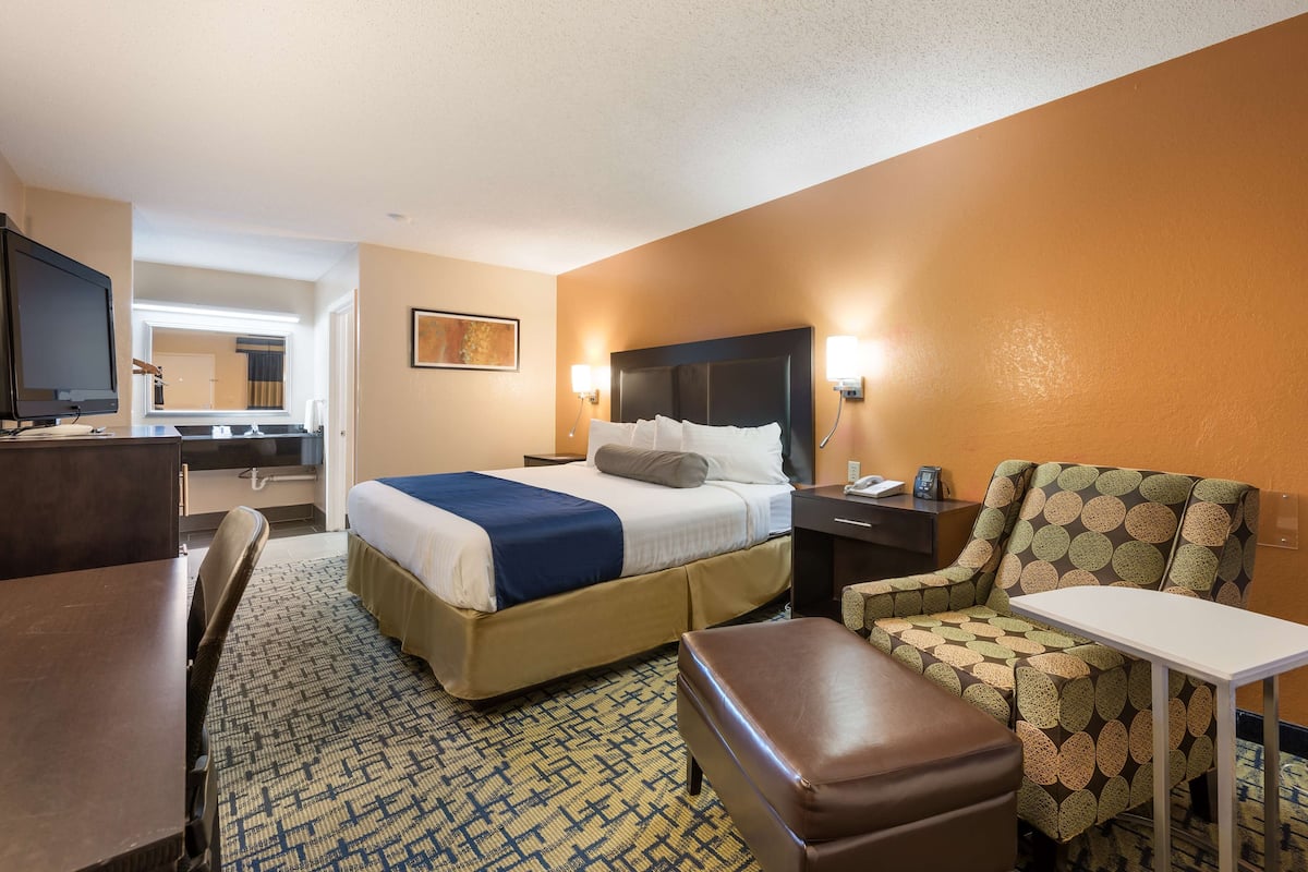 Une chambre d’hôtel comprenant un lit, un bureau, une chaise, une petite table et un téléviseur.