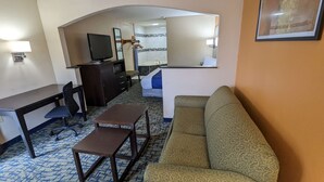 A hotel room with a sofa, a desk, a television, a dresser, and a bed. - SureStay Hotel by Best Western Meridian (Meridian)