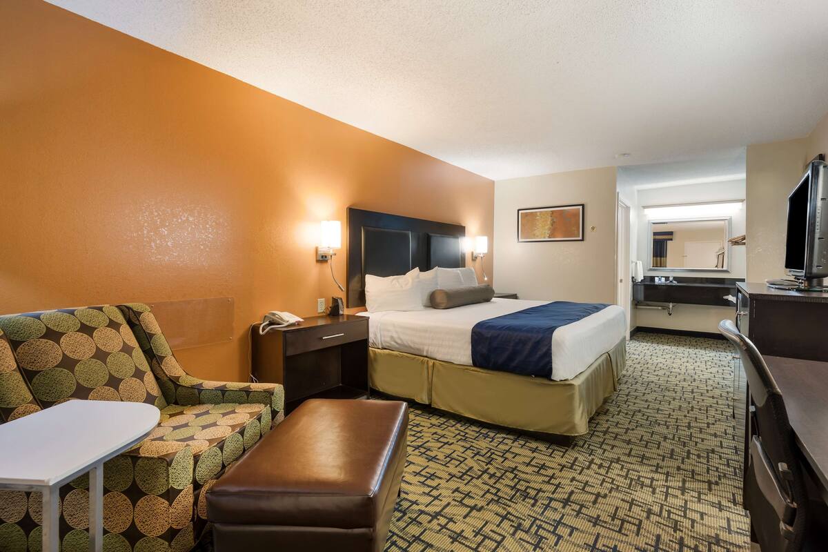 Une chambre d’hôtel avec un lit, un canapé, une petite table et un bureau.