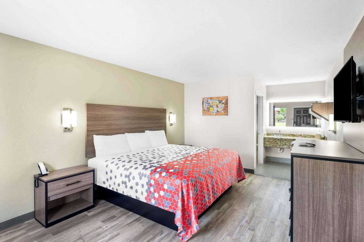 Una habitación de hotel con una cama, mesita de noche y un pequeño escritorio.