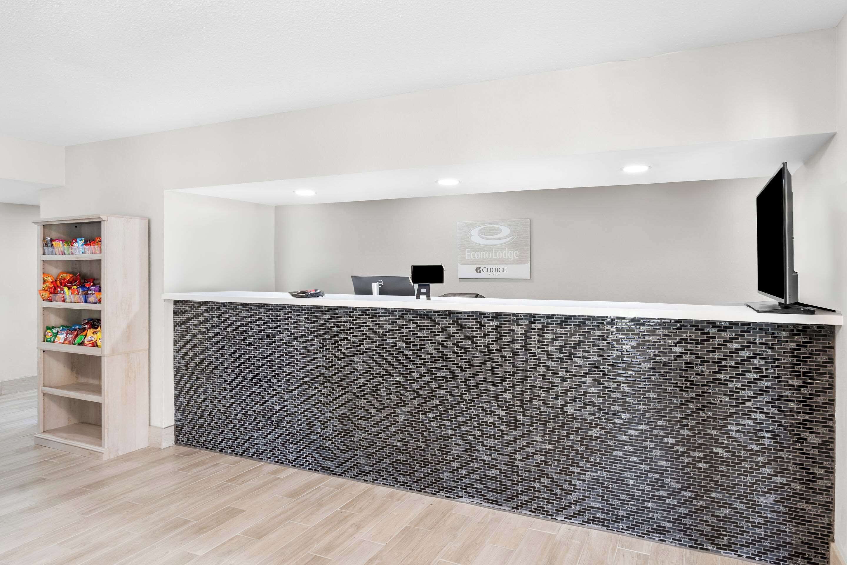 A reception area with a white counter, a tiled backsplash, and a sign for Econolodge.