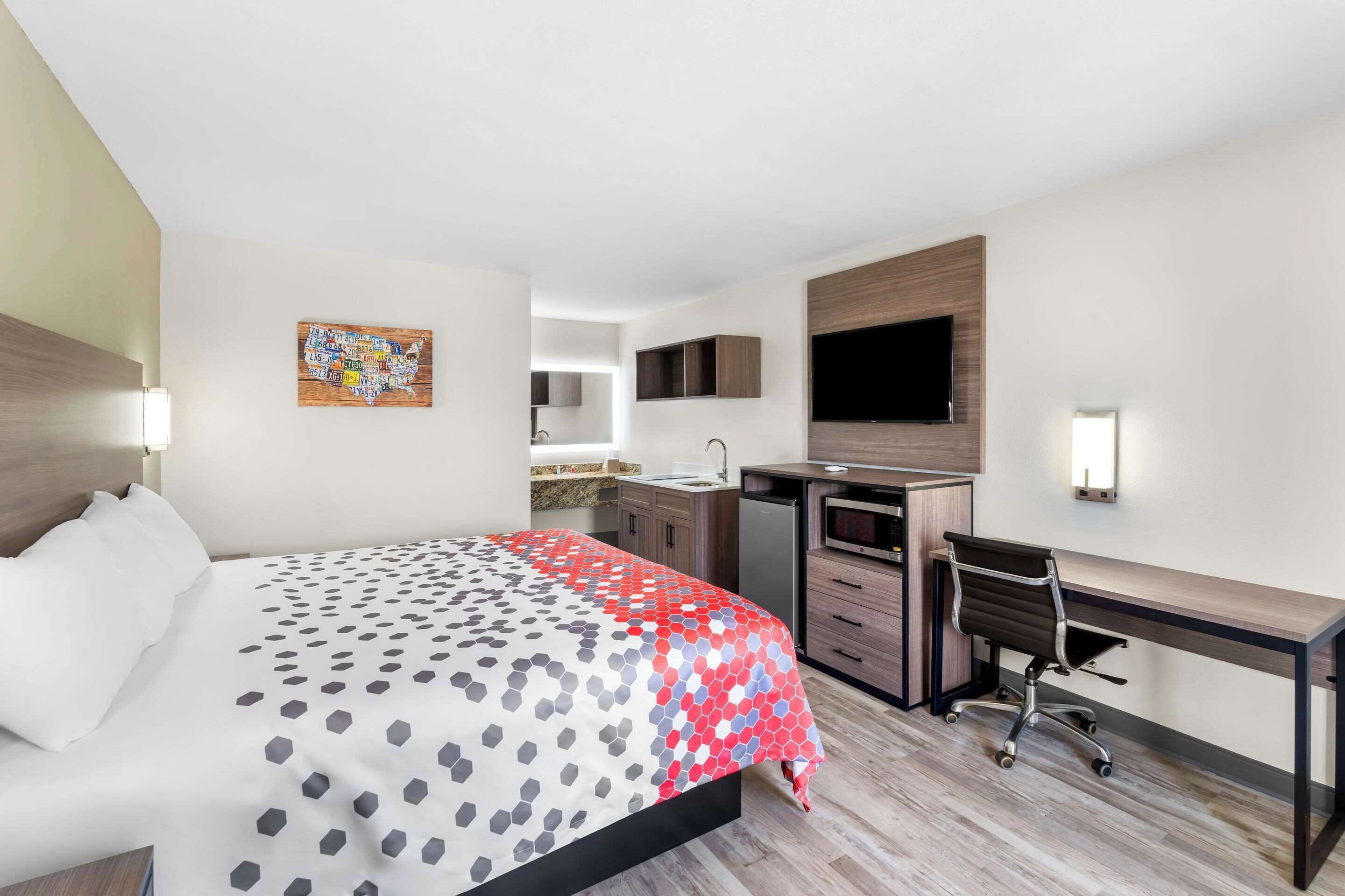 Une chambre d’hôtel avec un lit, un bureau et une kitchenette.