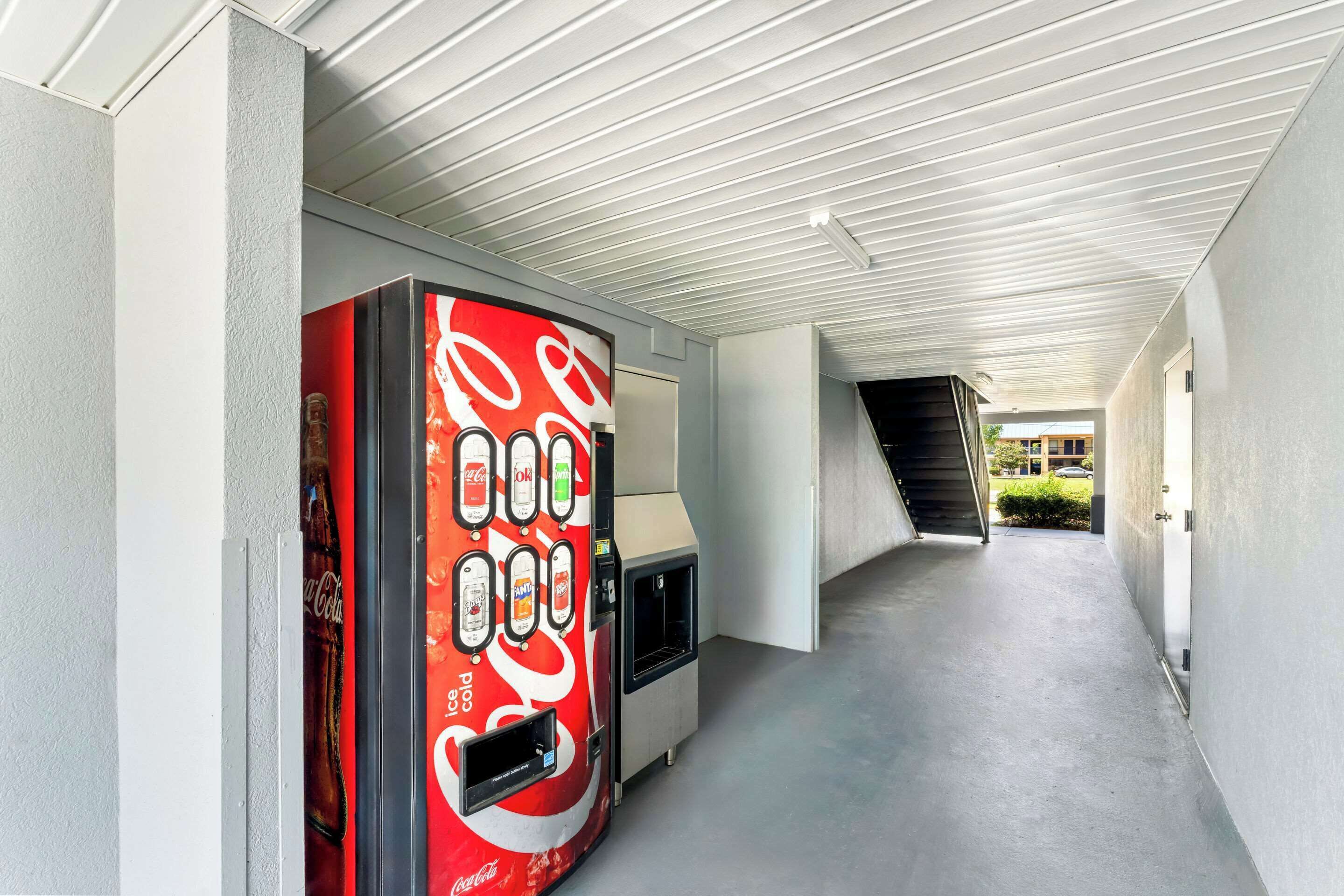 Corredor com uma máquina de refrigerantes Coca-Cola e uma escadaria.