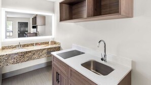 Un baño moderno con encimera de granito, lavabo doble y tocador de madera.