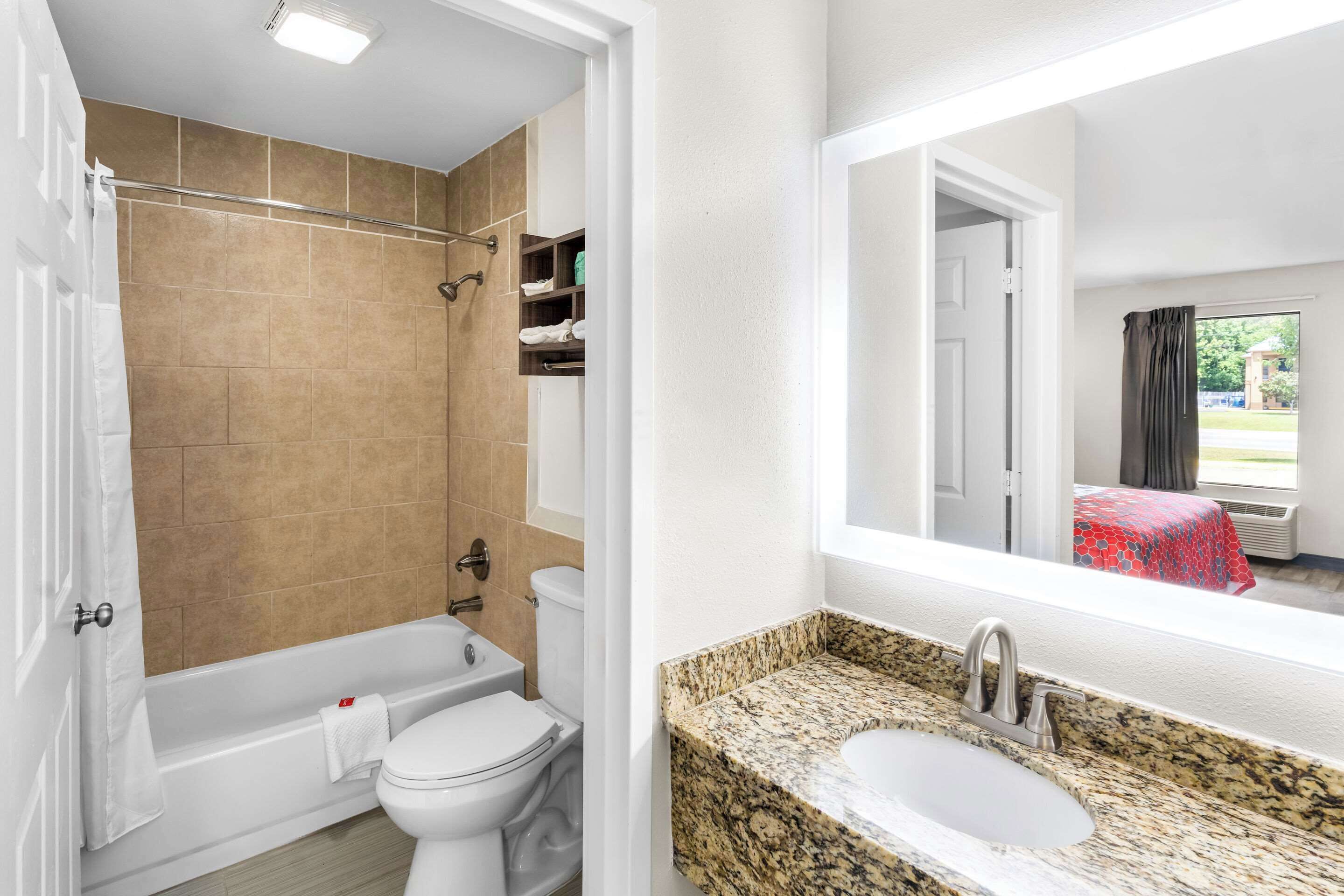 A bathroom with a bathtub, toilet, and shower. There is a vanity with a sink and a mirror.
