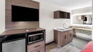 Una cocina moderna con microondas integrado, lavavajillas y un lavabo. Hay un televisor de pantalla plana montado en la pared sobre la encimera.