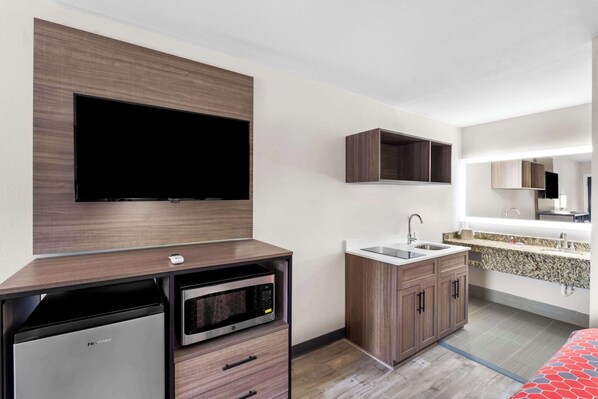 A modern kitchen with a built-in microwave, a dishwasher, and a sink. There is a flat-screen TV mounted on the wall above the counter.