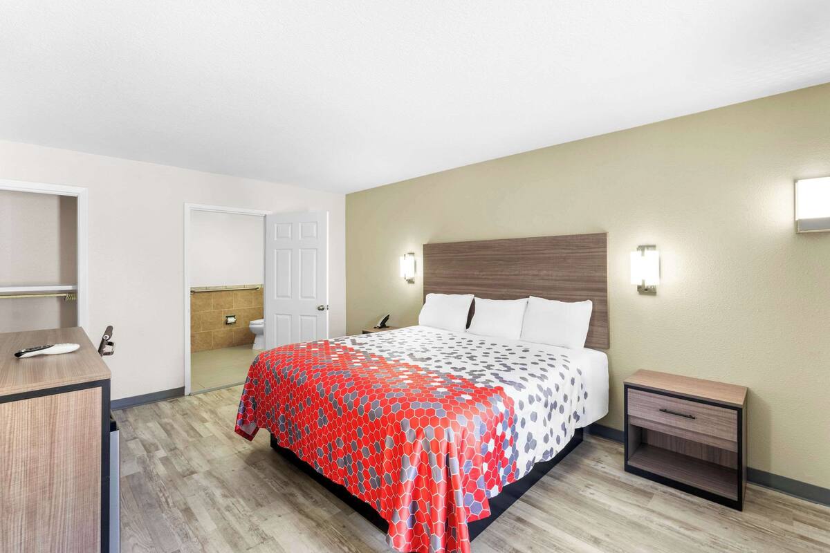 Una habitación de hotel con cama, mesita de noche y escritorio con silla.