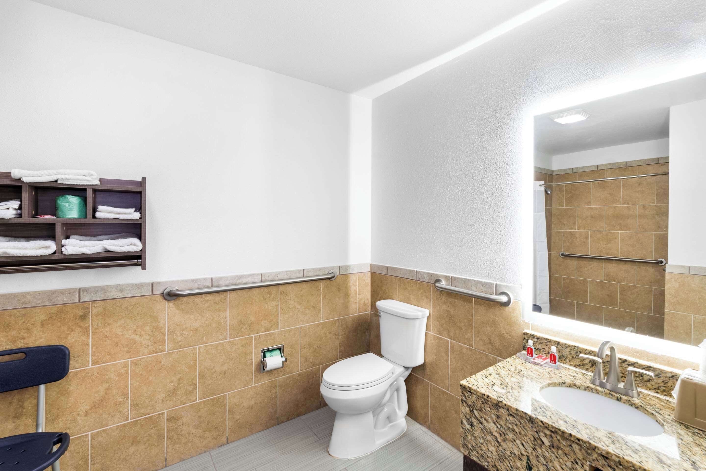 Un baño moderno con un inodoro blanco, un lavabo de granito y un espejo encima.