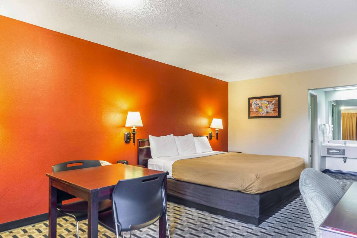 A hotel room with a bed, a desk, a chair, and a sofa.