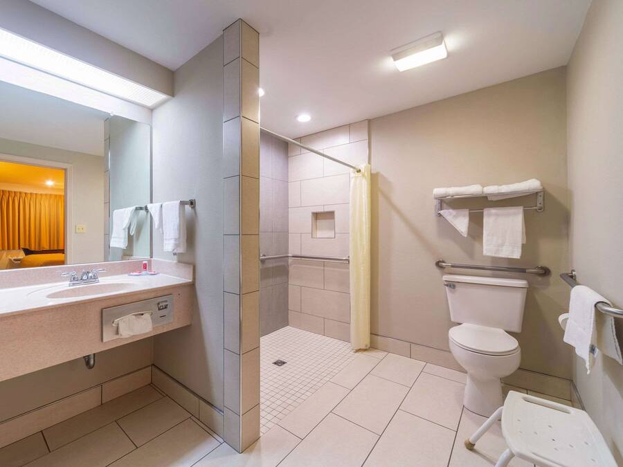 A modern bathroom with a sink, toilet, shower, and a mirror.