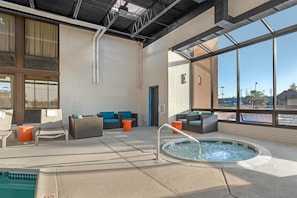 A pool area with a hot tub, lounge chairs, and a view through large windows. - Drury Inn & Suites Joplin (Joplin)
