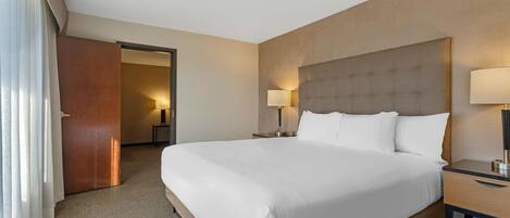 A hotel room with a large bed, bedside tables, a door, and a lamp.