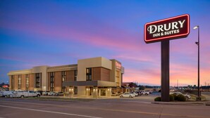 A Drury Inn & Suites building with a prominent sign, multiple parking spaces, and a clear sky.