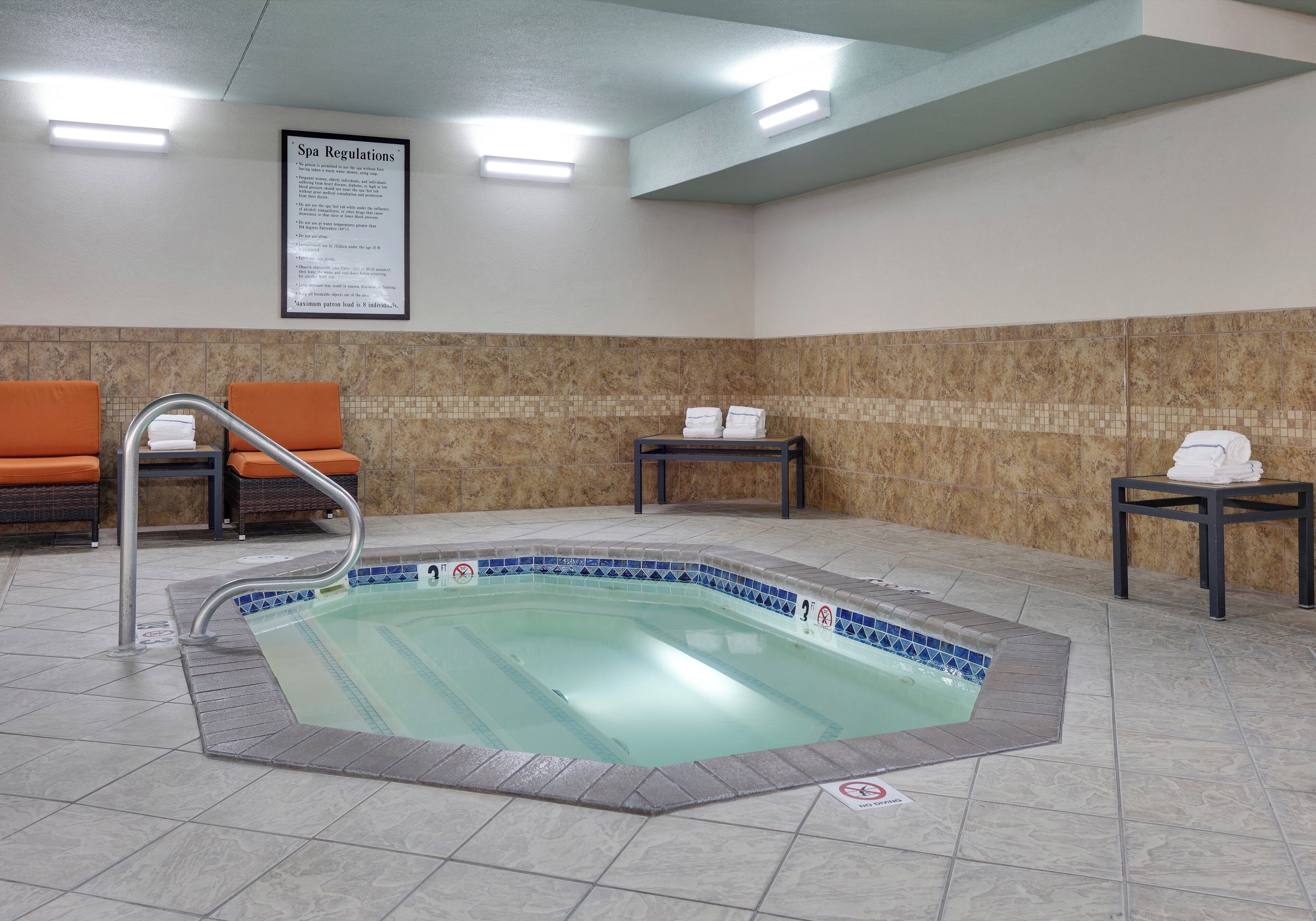 Un espace bien-être comprenant un jacuzzi, des sièges et un panneau indiquant les règles d’utilisation du spa.