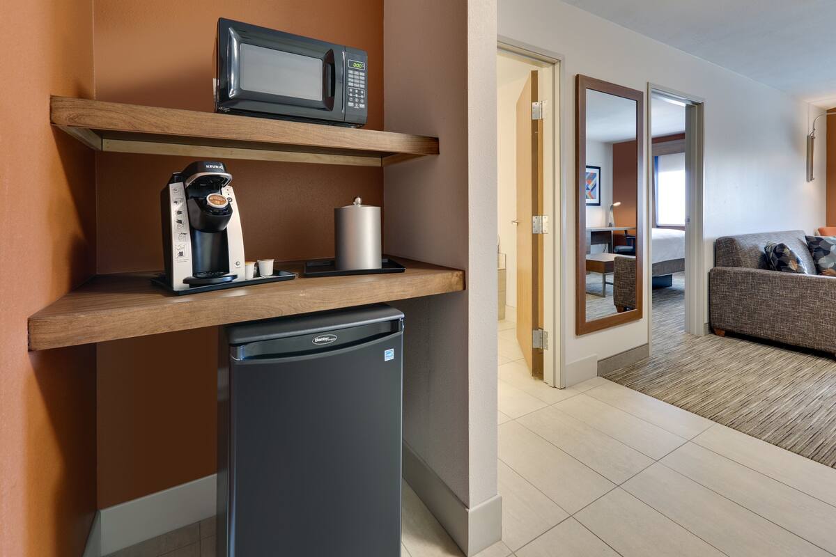 A compact kitchenette with a microwave, coffee maker, and refrigerator.