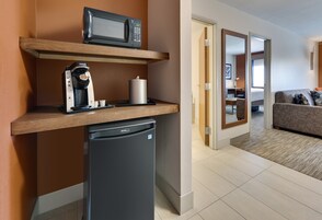 A compact kitchenette with a microwave, coffee maker, and refrigerator.