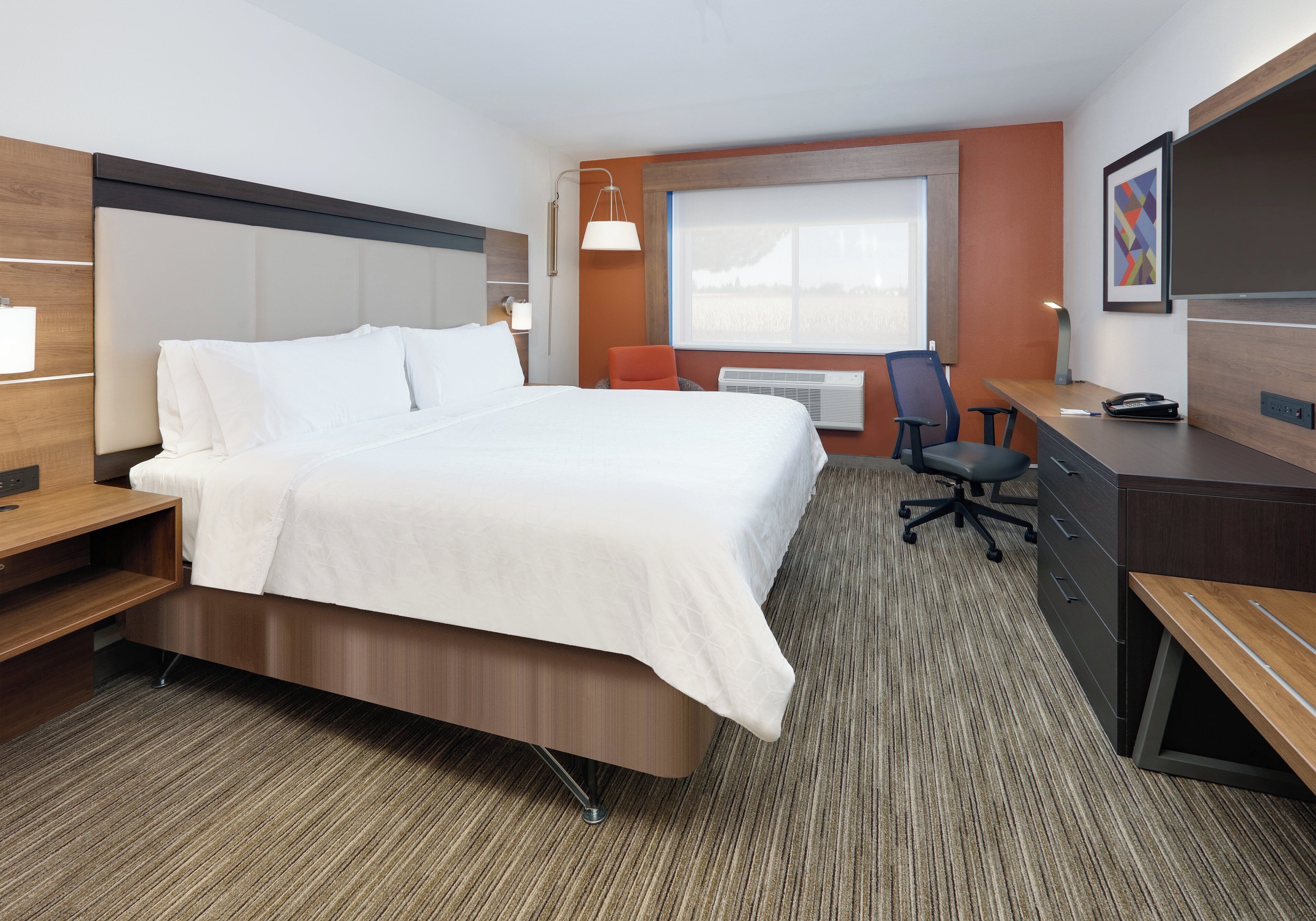 Une chambre d’hôtel avec un lit, un bureau, une chaise et une grande fenêtre.