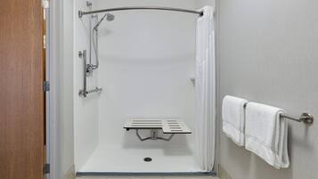 A shower with a handheld showerhead, a towel rack with towels, and a shower control panel.