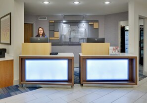 A reception desk with two computer stations, a sign for Holiday Inn Express Suites, and a vending machine.