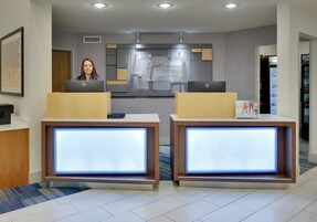 Una recepción con dos puestos de ordenador, un cartel de Holiday Inn Express Suites y una máquina expendedora.