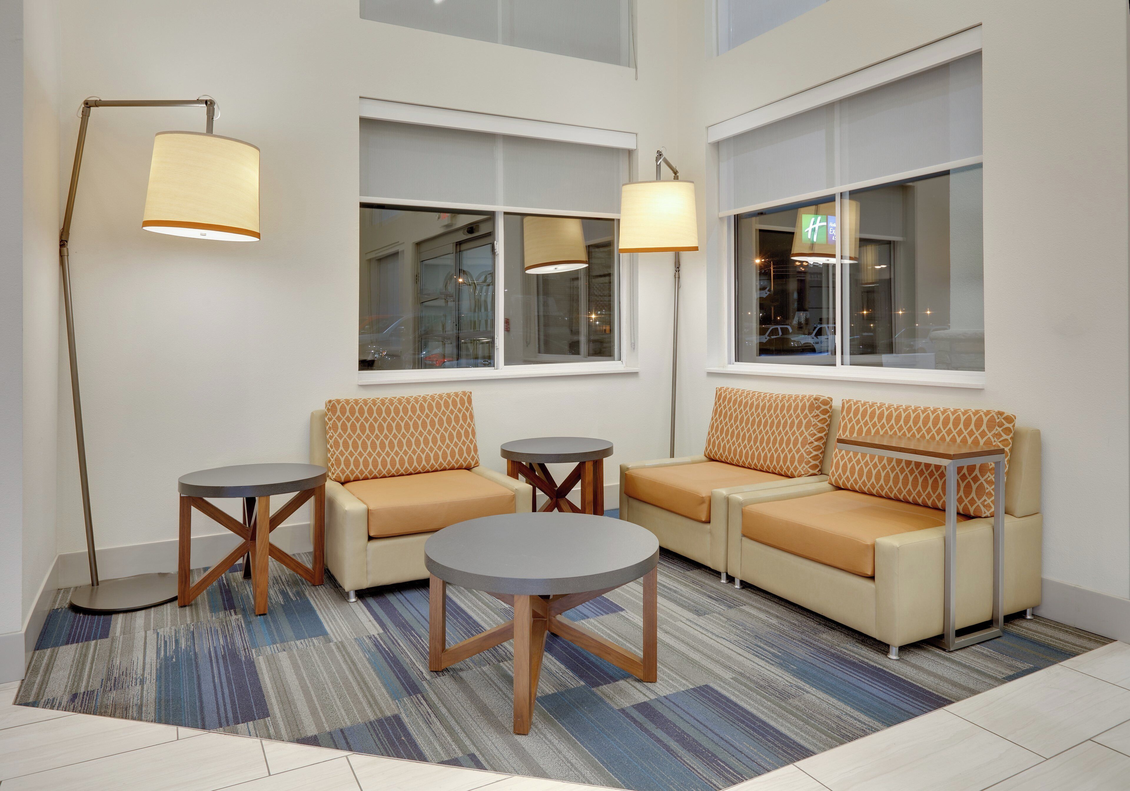 A modern hotel lobby with a sofa set, two small tables, and floor lamps.
