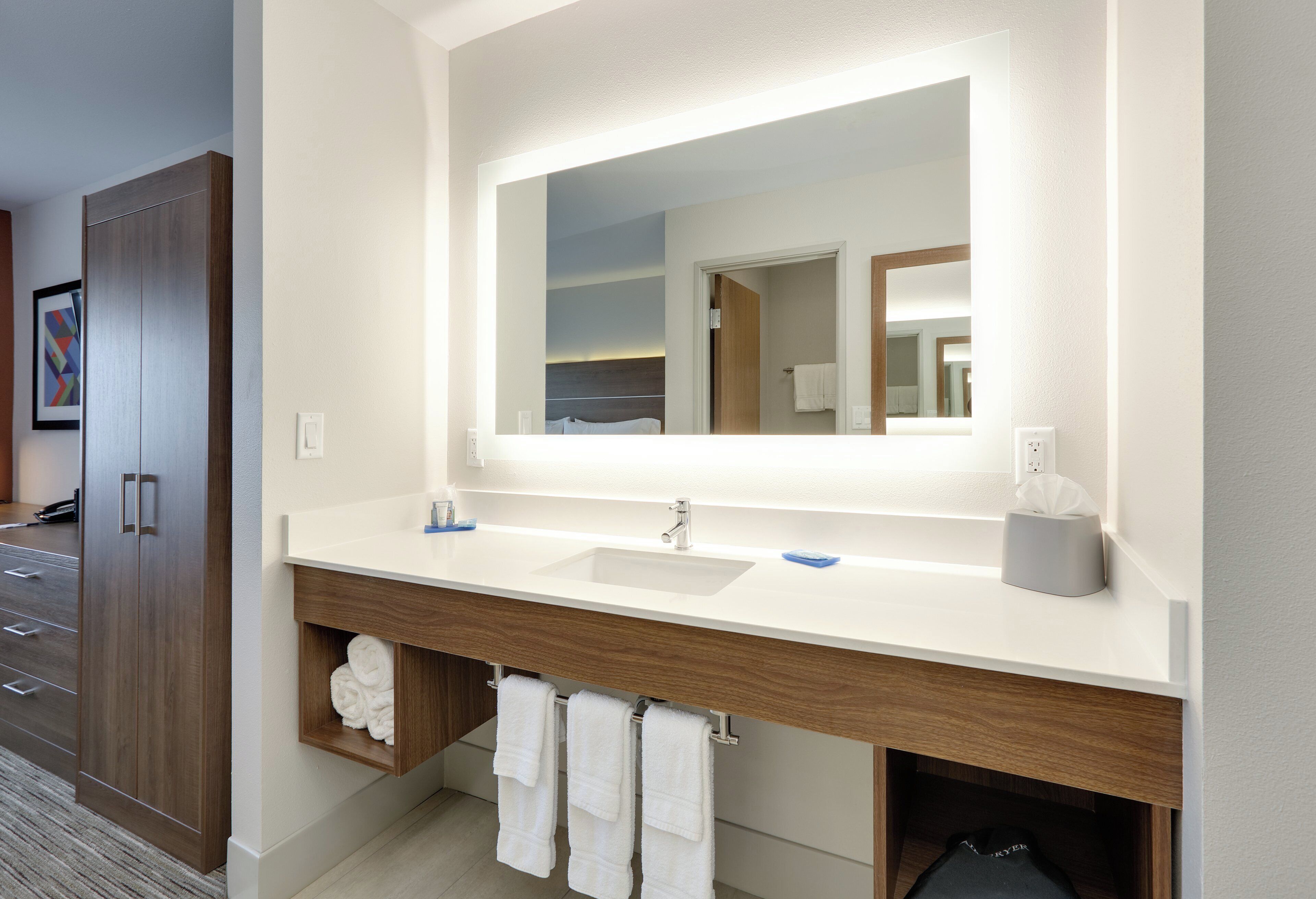 A modern bathroom with a large mirror, two sinks, and a towel rack.