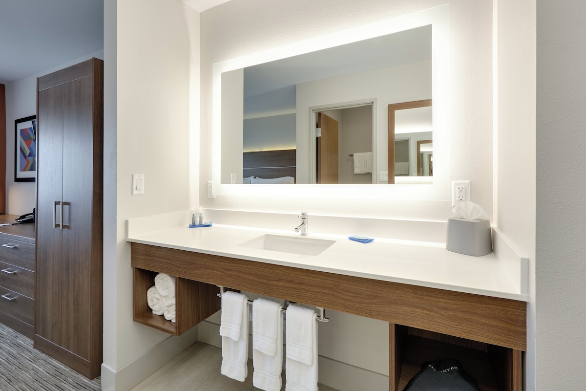 A modern bathroom with a large mirror, two sinks, and a towel rack.