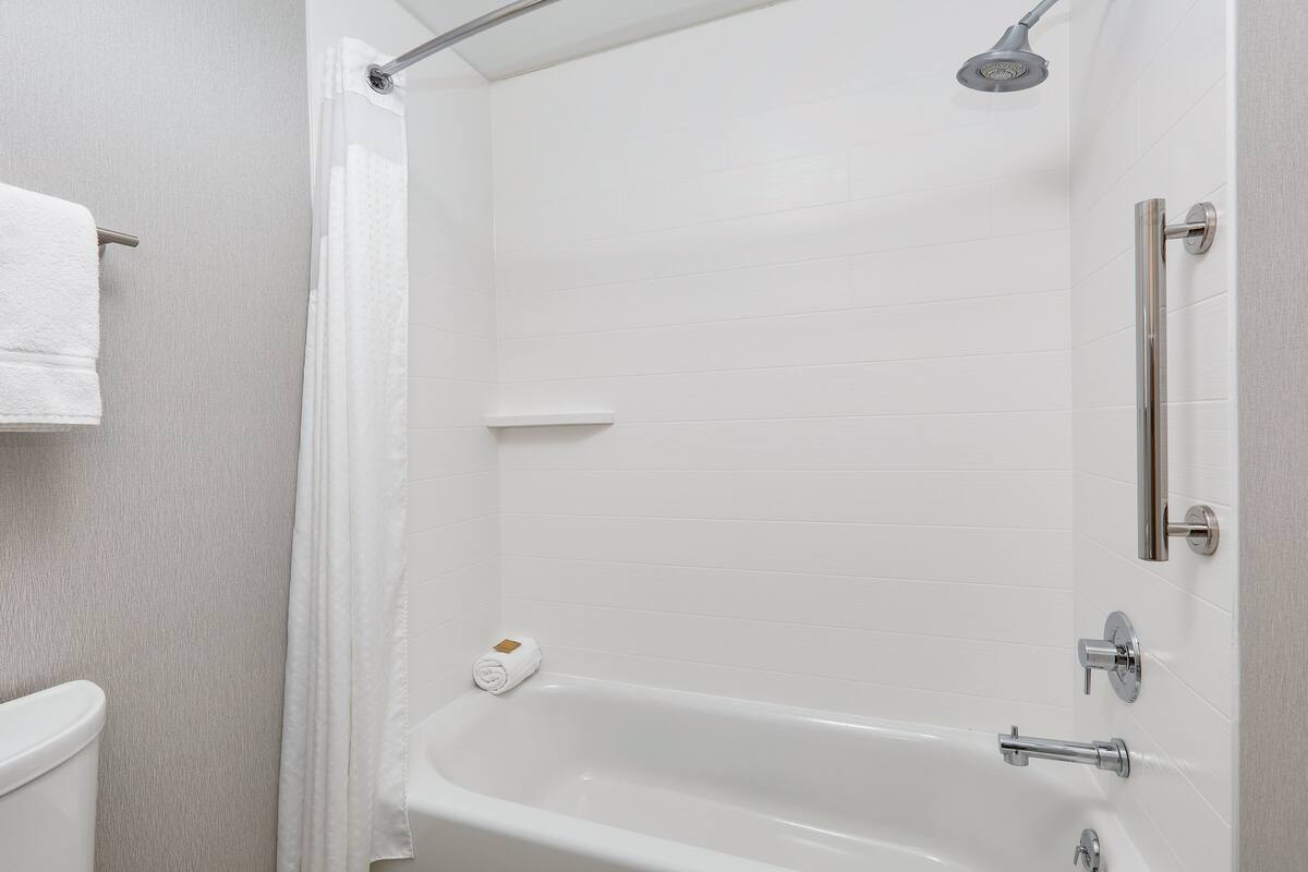 A modern bathroom with a white bathtub, a showerhead, and a towel rack.