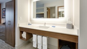 A modern bathroom with a large mirror, two sinks, and a wooden vanity.