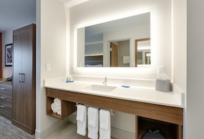 A modern bathroom with a large mirror, two sinks, and a wooden vanity.