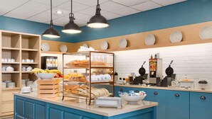 Mostrador de panadería con pan, pasteles y una máquina de café.