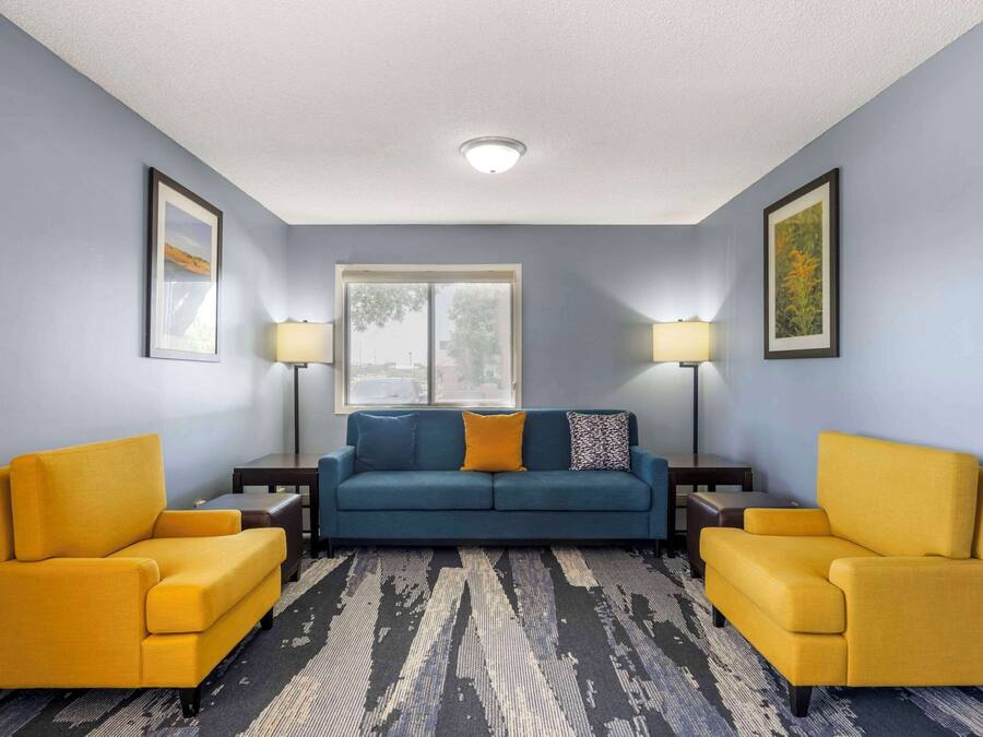 A living room with a blue sofa, two yellow armchairs, a patterned rug, and two side tables with lamps.