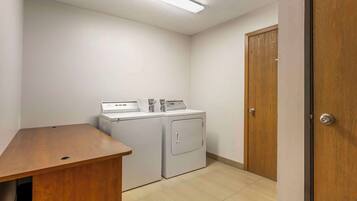 A laundry room with two washing machines, a wooden desk, and a door.