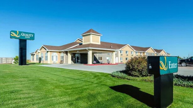 A Quality Inn hotel with a central entrance, a covered outdoor area, and a well-maintained lawn.