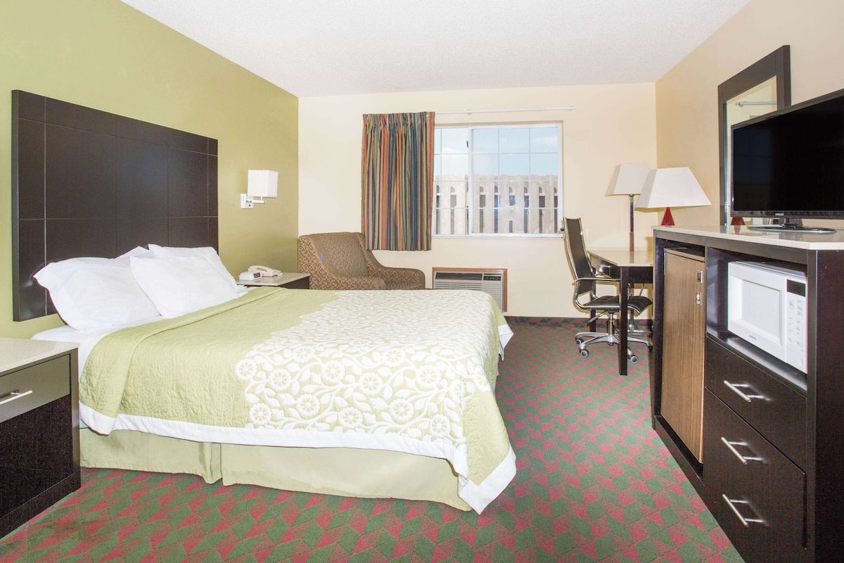 A hotel room with a bed, a desk, a chair, a television, and a wardrobe.