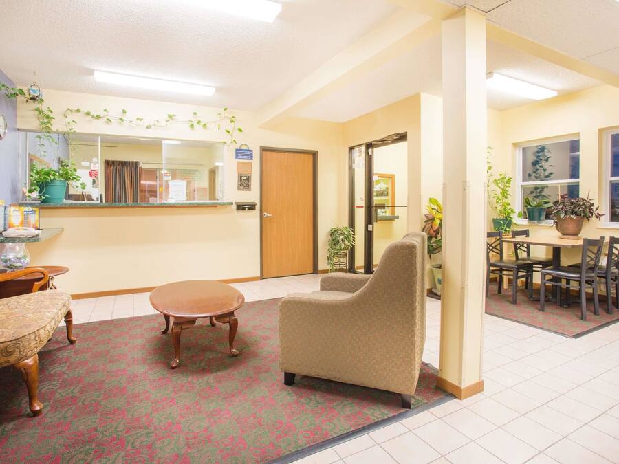 A hotel lobby with a reception desk, seating area, and a dining table with chairs.