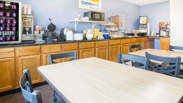 A breakfast area with a sign reading "Daybreak Breakfast," featuring a microwave, waffle maker, and various breakfast items on the counter. - Days Inn by Wyndham Lexington NE (Lexington)