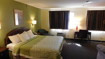 A hotel room with a bed, a desk, a chair, and a window with curtains.