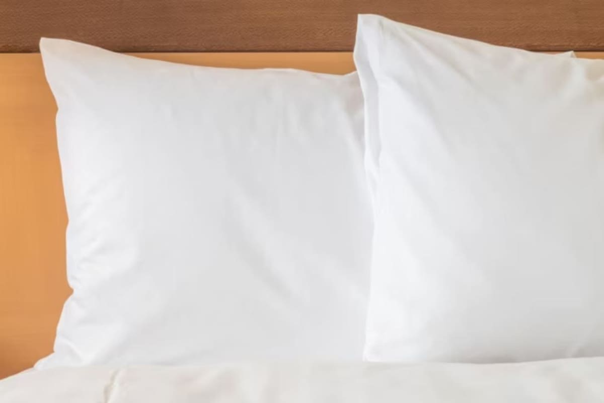 A bed with white bedding and a wooden headboard.