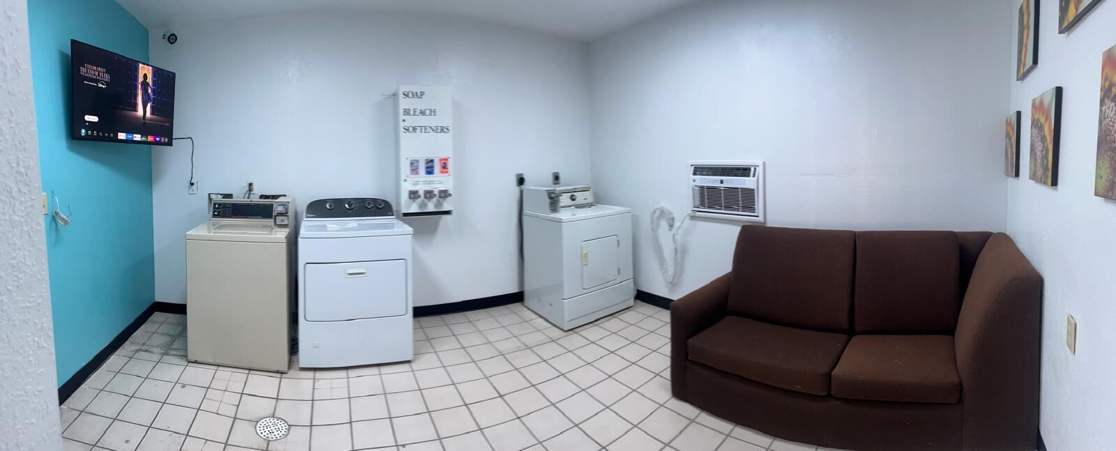 A laundry room with washers, dryers, and a sofa.